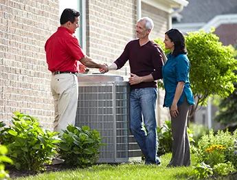 Heat Pump Repair Technician shaking hands with homeowner near heat pump's outdoor unit | Bennett Heating and Air LLC