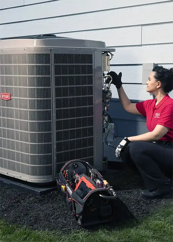 HVAC Technician servicing a heat pump unit outside with tool bag | Bennett Heating and Air