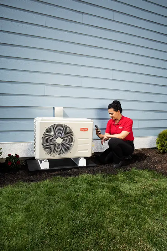 A female HVAC service technician checking a ductless unit outdoors portrait image | Bennett Heating & Air