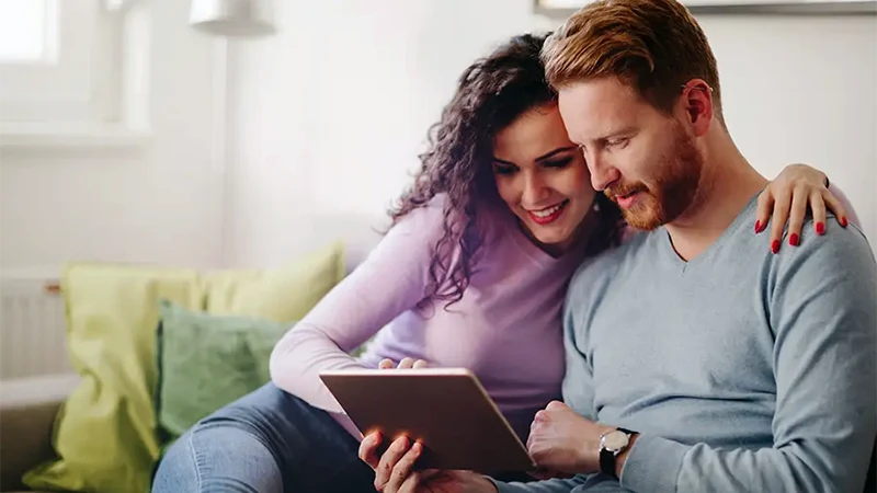 Comfortable couple on the couch using a tablet | Thank You | Bennett Heating & Air LLC