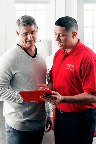 HVAC Technician standing beside a customer explaining HVAC maintenance plans | Bennett Heating and Air LLC